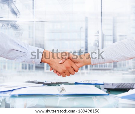 two business men and woman shaking hands, close businesspeople handshake after sign up documents contract, modern office desk over window city buildings