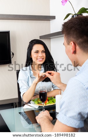 marriage proposal, man putting an engagement ring on woman finger, young happy couple dinner romantic date at restaurant, sitting at table celebrating