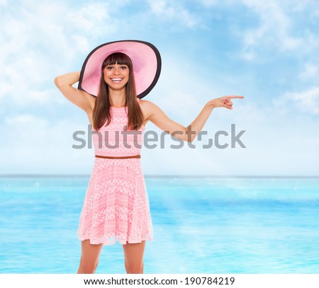summer vacation woman point finger side empty copy space blue sky ocean beach background, wear pink dress and hat happy smile, young girl holiday on sea sunny day