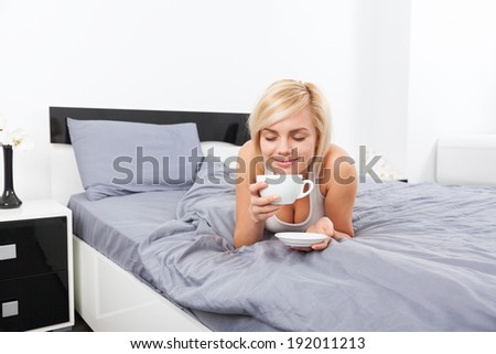 woman hold cup of coffee smell closed eyes dream on bed, young blond girl happy smile morning bedroom home