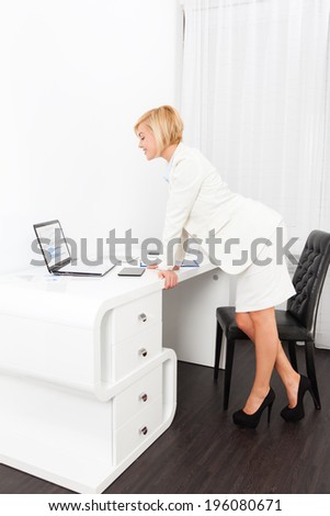Businesswoman using laptop computer, looking at screen report document with finance chart, diagram, young business woman at modern bright office desk