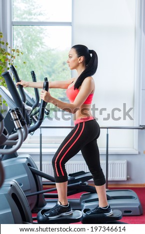 Fit woman sport exercising at the gym on an x-trainer cardio machine, fitness center