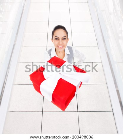 Business woman happy smile hold gift box in hands. Businesswoman full length portrait top angle view in modern office