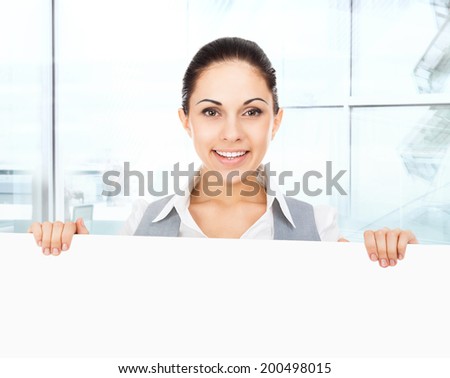 businesswoman holding a blank white card board, signboard, showing an empty bill board, young business woman happy smile in modern office