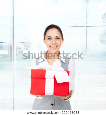 Business woman happy smile hold red gift box in hands. Businesswoman in modern office