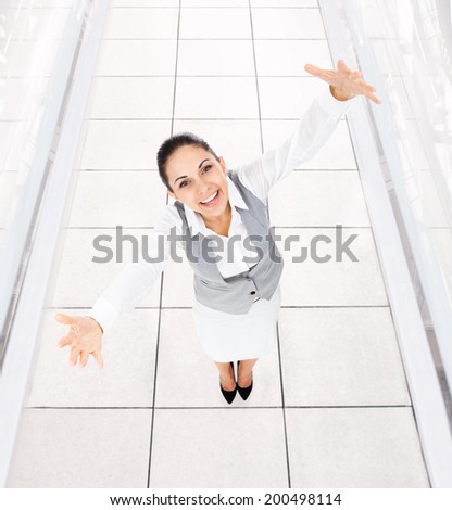 Business woman excited hold hands up raised arms palms, surprised happy smile business woman full length portrait top angle view in modern office