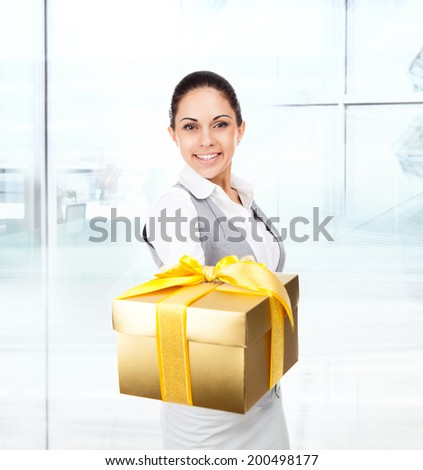 Business woman happy smile hold golden gift box in hands. Businesswoman in modern office