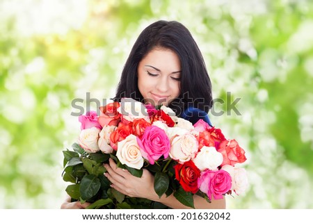 beautiful woman with big roses bouquet smile smell, elegant dress over green tree park outdoor background, concept of 8 march holiday or valentine\'s day