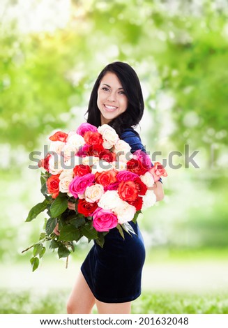 beautiful woman with big roses bouquet smile, elegant dress over green tree park outdoor background, concept of 8 march holiday or valentine\'s day
