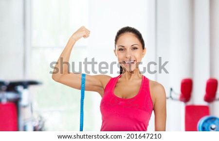 sport fitness woman measure with tape flexing show her biceps muscles in gym, young healthy smile girl athletic body, perfect figure