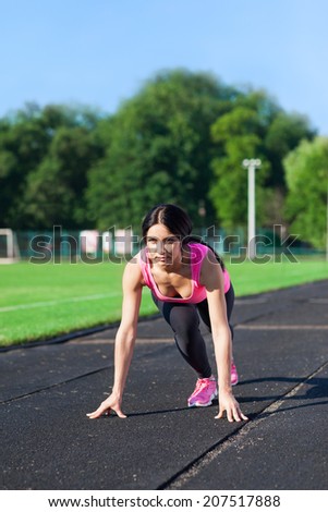 Woman start position on stadium, ready to run summer outdoor training