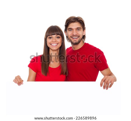 young happy couple hold blank board with empty copy space, man and woman smile, wear red shirt isolated over white background