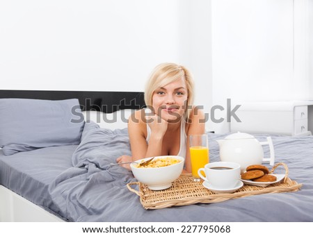 Breakfast in bed, young woman eating cornflakes drinking coffee. beautiful girl lying on bed smiling morning
