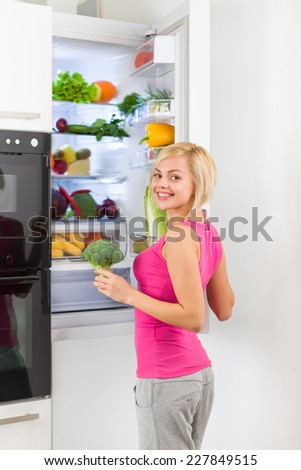 young woman refrigerator open door, pretty girl smile dieting healthy food vegetables and fruits, modern kitchen