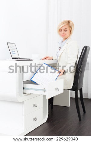 business woman hide document in desk box, businesswoman sitting in modern bright office, concept of dirty accounting corruption
