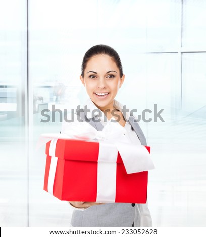 Business woman happy smile hold red gift box in hands. Businesswoman in modern office