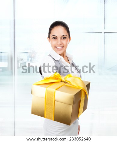 Business woman happy smile hold golden gift box in hands. Businesswoman in modern office