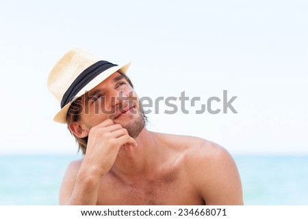 man smile on beach Handsome young male think look up to empty copy space, dream hold hand finger on chin wear hat