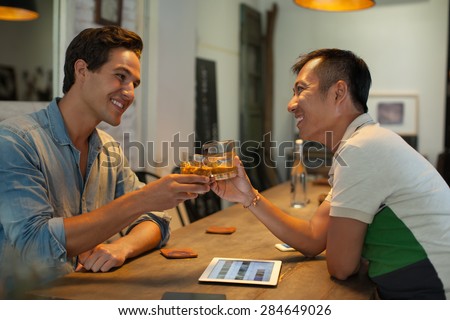 Two Men Cheers Toast Drink Ice Coffee, Asian Mix Race Friends Guys Happy Smile Sitting at Cafe Natural Light
