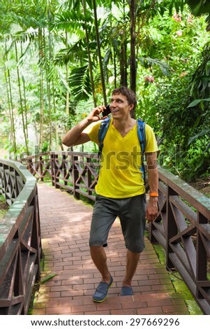 Tourist man using cell smart phone call smile summer vacation green tree asia park travel communication