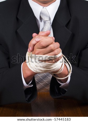 stock photo Business man in a suit sitting at the table with tied hands