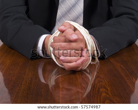 Business man in a suit sitting at the table with tied hands