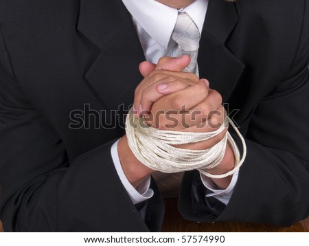 stock photo Business man in a suit sitting at the table with tied hands