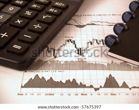 Calculator and notepad on the stock charts graph paper