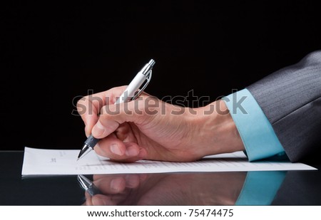 businessman\'s hand with pen on the table over black background