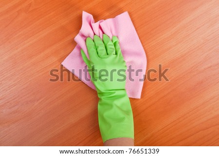 Cleaning furniture table in green glove with pink sponge