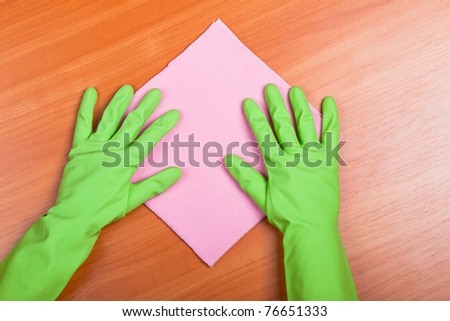 Cleaning furniture table in green gloves with pink sponge