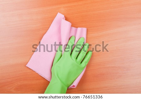 Cleaning furniture table in green glove with pink sponge