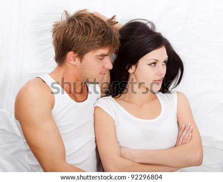 young upset couple lying in a bed, having problem. Divorce and separation conflict sad looking at camera, negative emotions concept, top view.