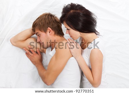 young upset couple lying separate in a bed, having conflict problem. sad negative emotions concept, top view.