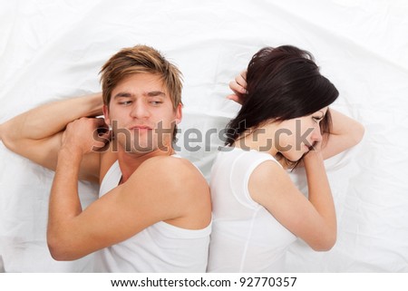 young upset couple lying separate in a bed, having conflict problem. sad negative emotions concept, top view.