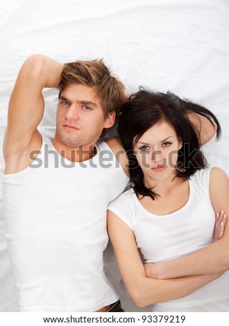 young upset couple lying in a bed, having problem. Divorce and separation conflict sad looking at camera, negative emotions concept, top view