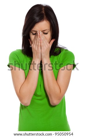 upset pretty woman cry covering her face by hand closed eyes, young girl wear green shirt, isolated over white background, concept of depression, stress and problems, pain