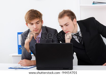 young business people working in team together on laptop computer, two concentrated businessmen looking on computer screen decide problem, businesspeople sitting at desk office