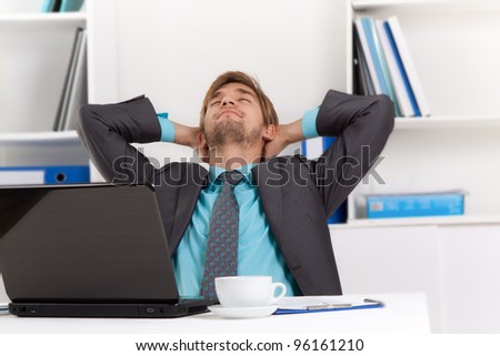 Relaxed young business man happy smile sitting at the desk, handsome businessman relaxing hold hand on head