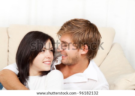 beautiful young happy couple  laying on couch happy smile looking to each other, portrait of lovely young man and woman hug, embrace on the sofa