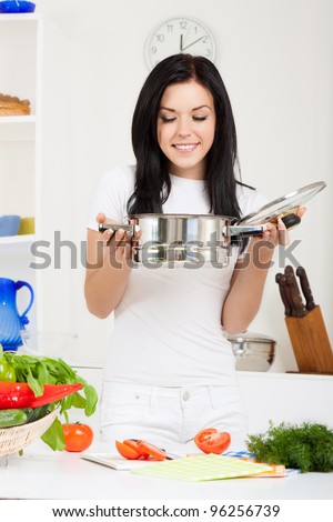 portrait of beautiful woman hold pan with ready meal, soup, boiler in the kitchen, happy smile