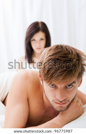 young upset couple lying in a bed, having conflict problem. sad negative emotions concept