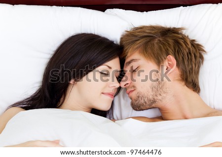 young lovely couple lying in a bed, happy smile touching nose sleep with closed eyes