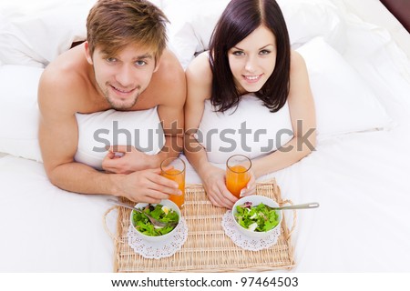 happy young couple eat breakfast in bed in morning, lovely couple lying in a bed, happy smile looking at camera, concept of honeymoon, valentine day top angle view