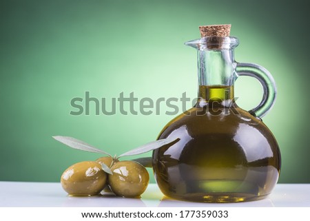 Olive oil bottle and olives on a green spotlight background