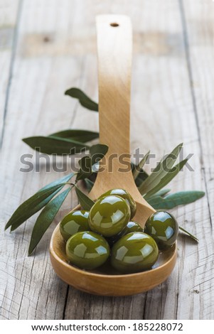 Wooden spoon with olives and oil on the kitchen table