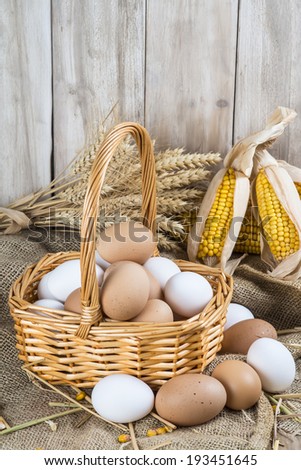 Basket with fresh range eggs and cereals to feed hens in the hen house