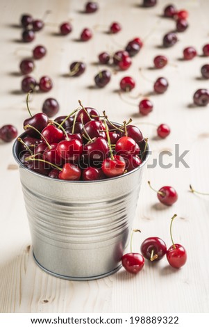 Little brass bucket of cherries on a wooden table
