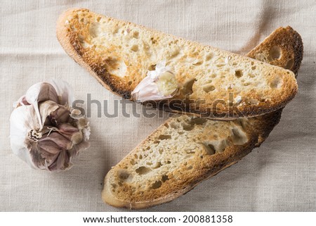 Garlic bread toasts and garlic cloves on a napkin