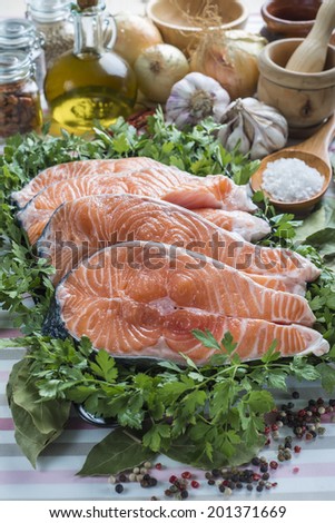 A platter with sliced fresh salmon and ingredients to cook it on the table of the kitchen